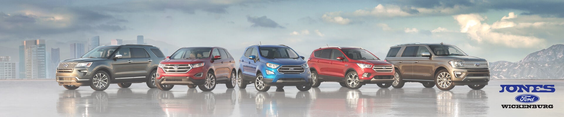 A Full lineup of new Ford trucks, cars and SUVs parked side-by-side with a scenic mountain backdrop with the Jones Ford logo shown.